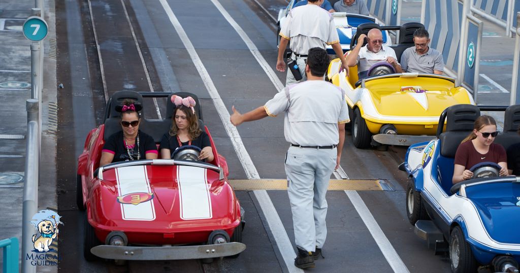 Cast member signals to guests they are good to press the gas pedal in their race car in Magic Kingdom