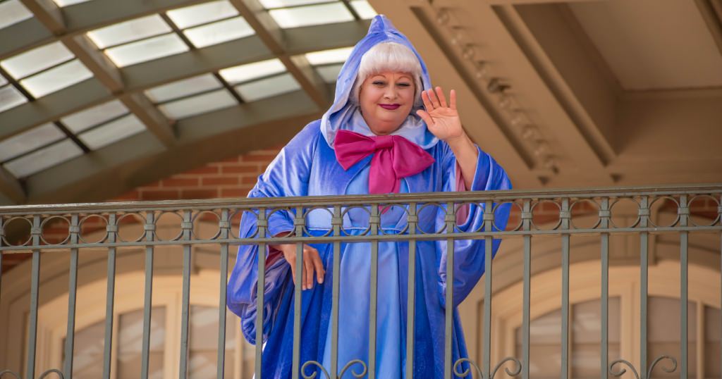 Fairy Godmother waiving from the Magic Kingdom train station to guests.